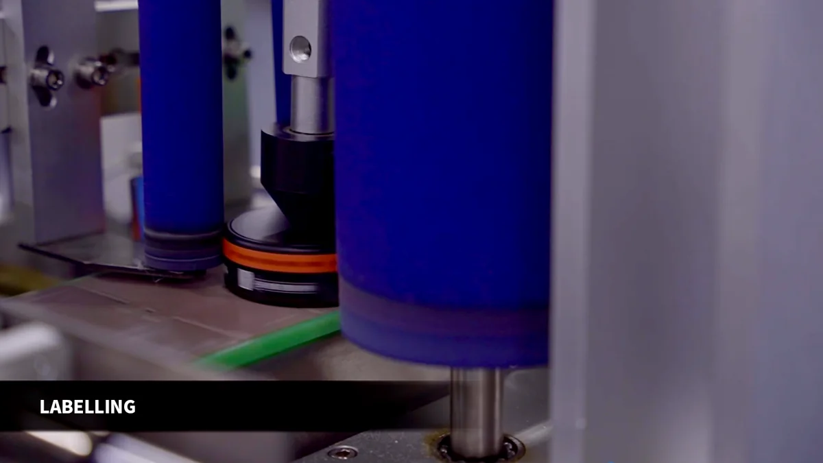Containers passing through rollers on a labelling line