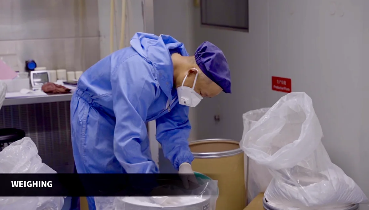 Operator weighing powdered material at a production workstation